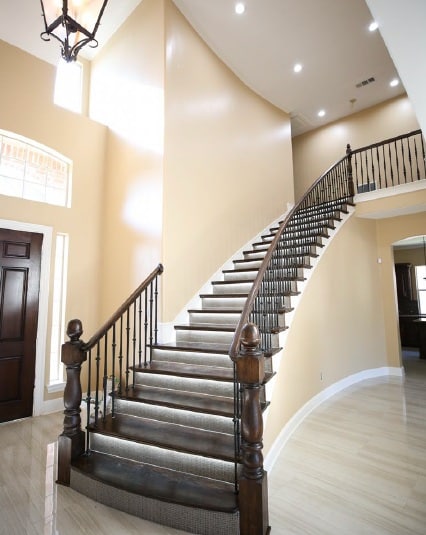 Curved staircase with dark wood treads and light tile flooring